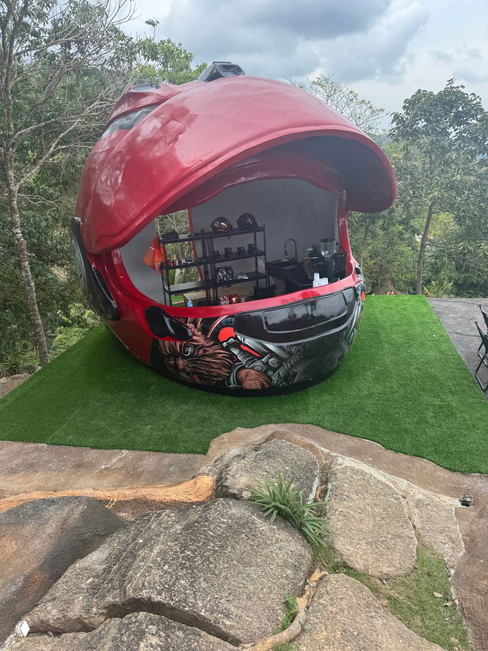 Бар в форме большого красного мотоциклетного шлема с открытой передней частью, внутри видно барную стойку и оборудование.