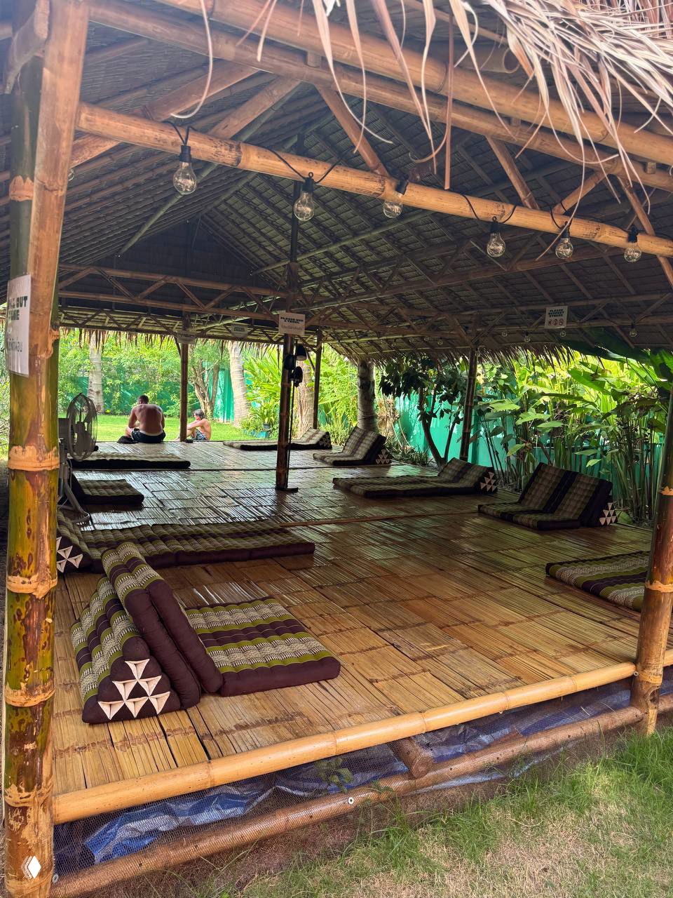 Открытая бамбуковая площадка с матами и подушками для йоги/релаксации под крышей — зона для занятий и отдыха на территории сауны Vihara.