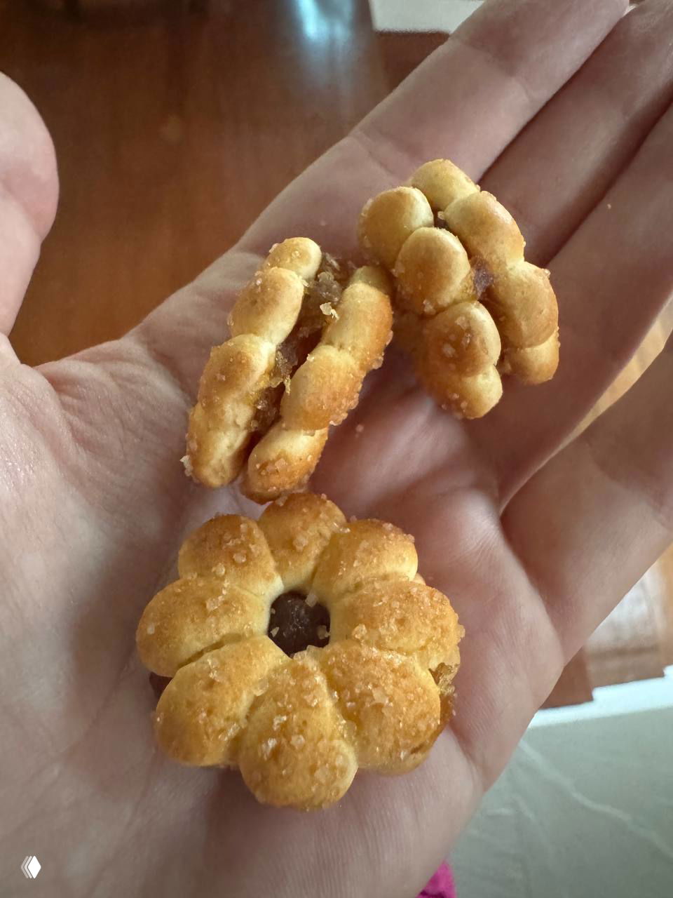 Крупный план: в руке автора лежат цветочные печенья с ананасовой повидлой между слоями, видна сахарная крошка и текстура.