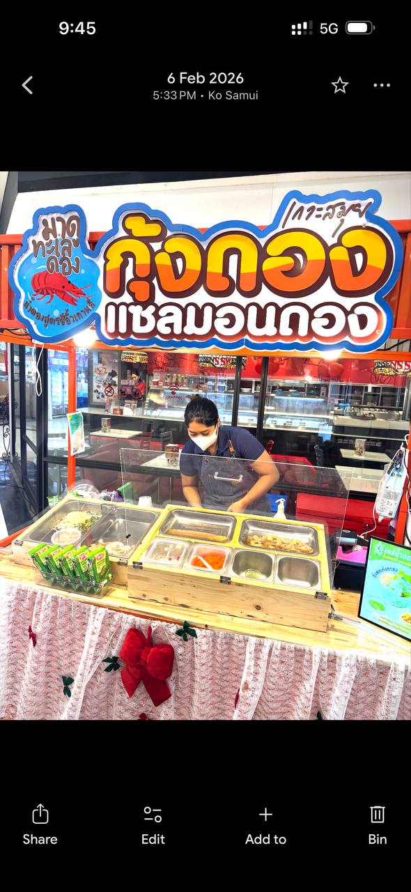 Ларёк в Лотус Чавенг с большим ярким знаком и прилавком ингредиентов; продавец в маске готовит salmon don на входе в фудкорт.