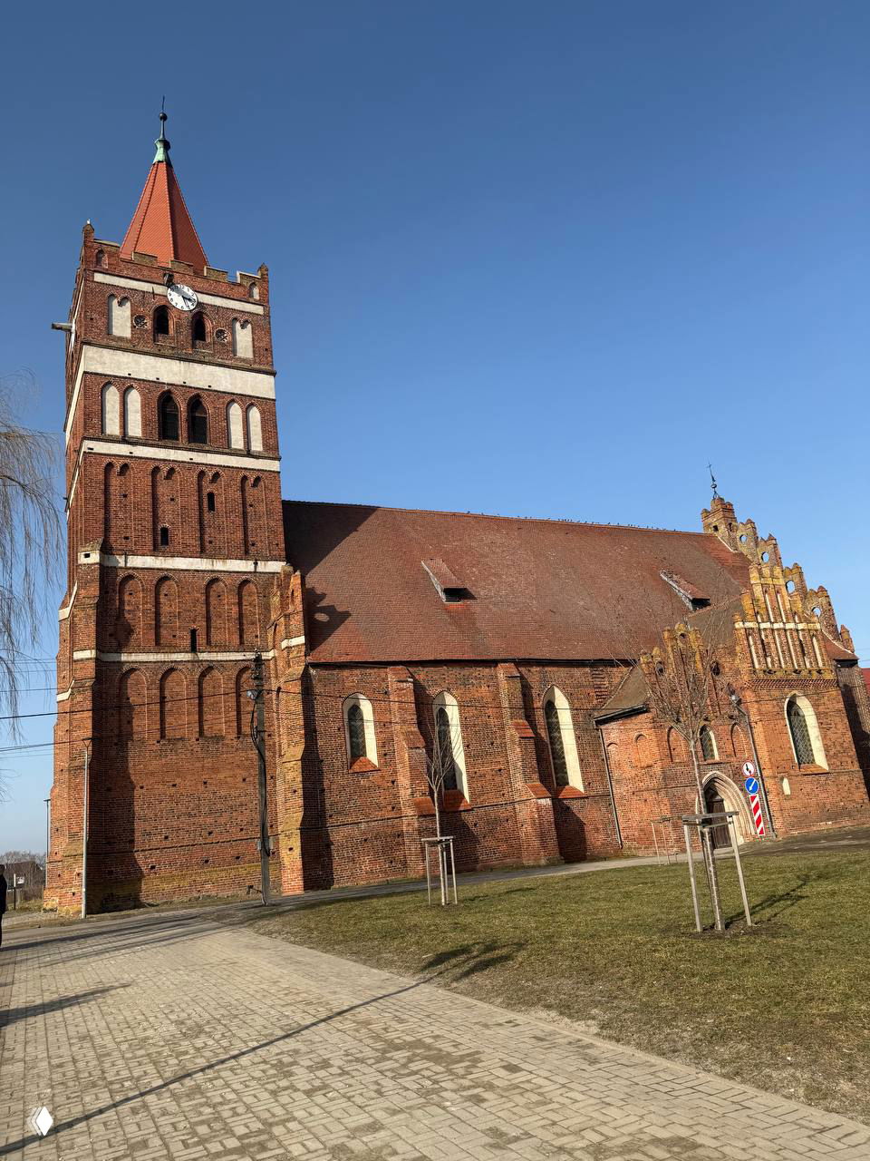 Фридландская (Святого-Георгиевская) кирха — мощное кирпичное здание с высокой башней и готическими элементами на фоне ясного весеннего неба.