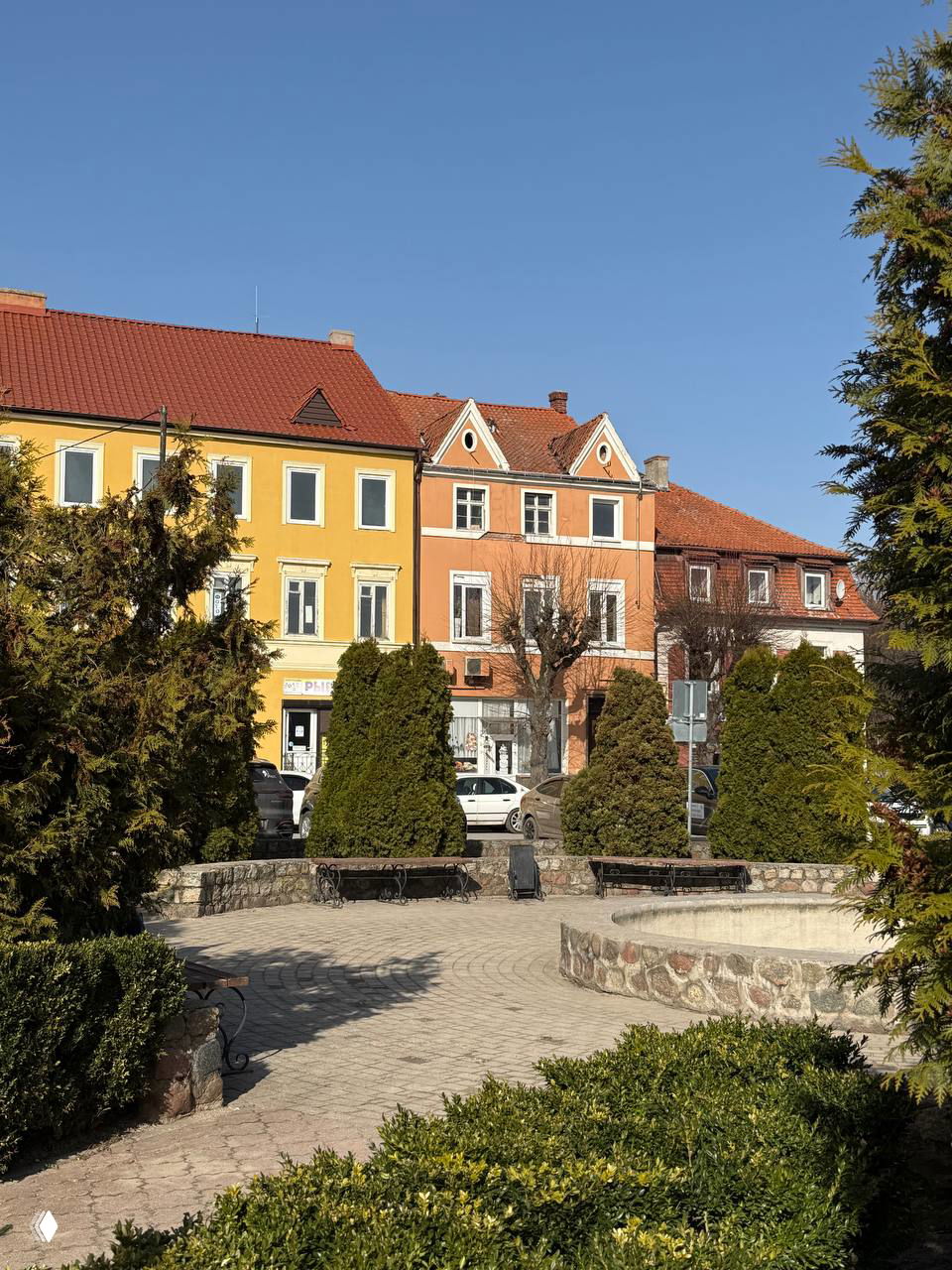 Цветные фасады домов на центральной площади Правдинска, скамейки и приусадебные зелёные насаждения в оформленной пешеходной зоне.