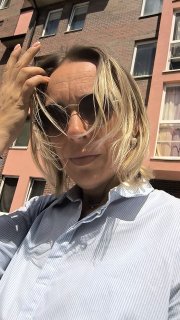 Селфи женщины в солнцезащитных очках на фоне кирпичного фасада жилого дома — портретный кадр риэлтора в Калининграде для профиля и контактов.