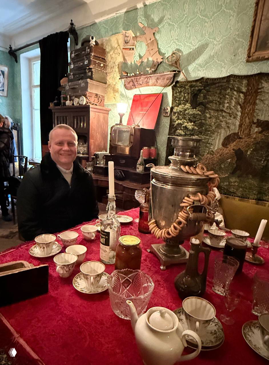 Чайный стол в комнате-музее: самовар, чашки, варенье и мужчина за столом — бытовая сценография в коммуналке