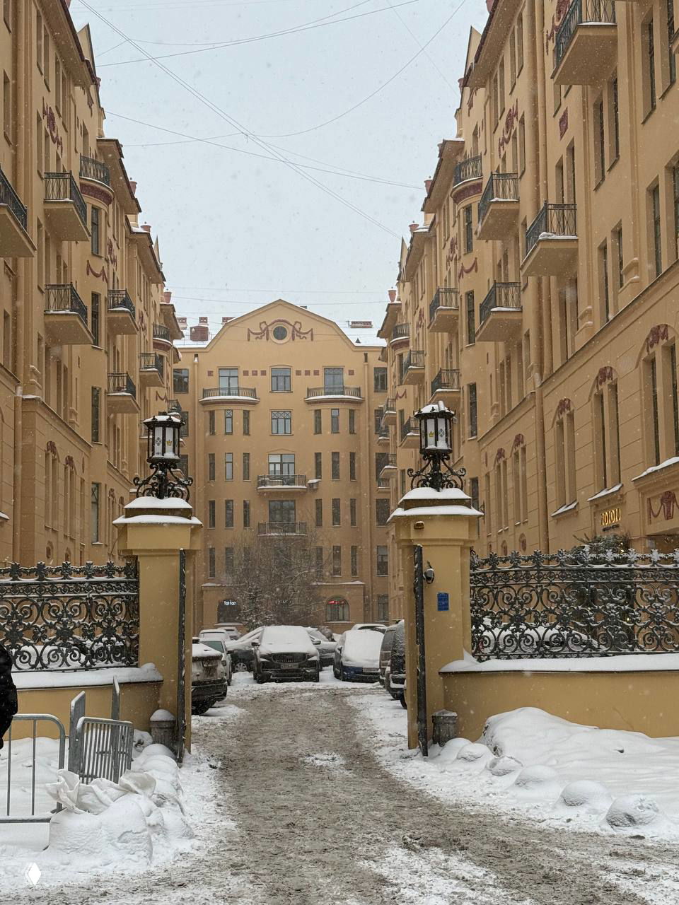 Входные ворота и парадный двор многоэтажного доходного дома, снег и архитектурный фасад в стиле неоклассицизма