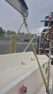 Фрагмент палубы и рангоута мелкой яхты в дождливую или пасмурную погоду: тросы, поручни и мокрая поверхность кокпита.