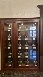 Деревянная витрина с рядами бюстов и экспонатов, отражающая музейную экспозицию и находки из экспедиций в интерьере РГО.