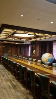 Длинный стол заседаний с кожаными креслами и большим глобусом в зале Учёного совета Русского географического общества, интерьер и светильники.