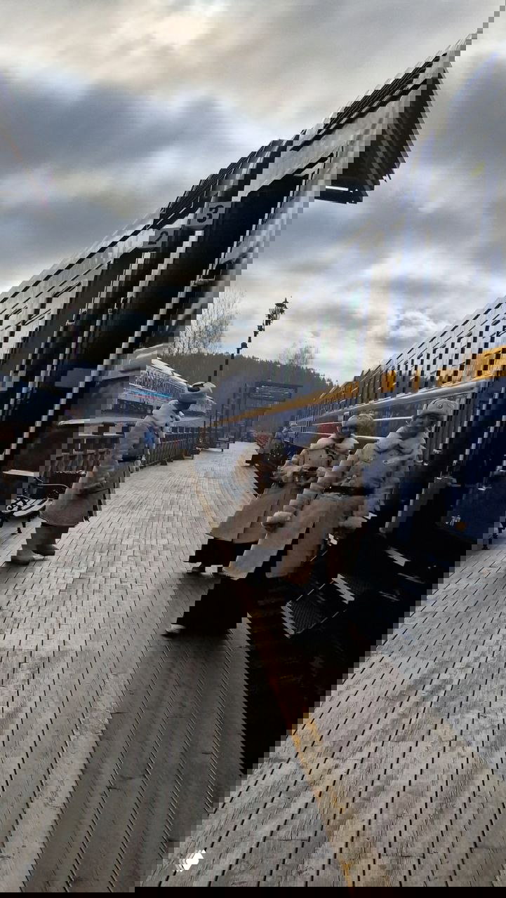 Платформа станции с ретровагоном и сотрудниками в исторических костюмах: деревянный настил, тёмно‑синие вагоны и прохладная погода в несезон.