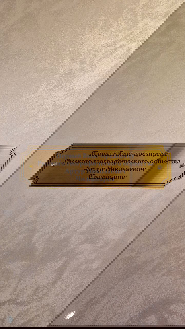 Бронзовая табличка с посвящением Первому Вице‑президенту РГО Артуру Николаевичу Чилингарову на светлой стене внутри штаб‑квартиры общества.