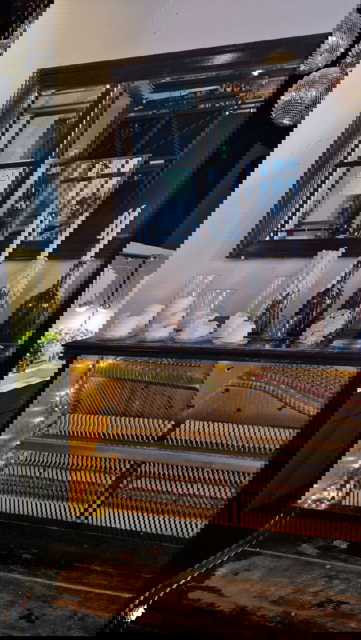 Интерьер ресторана: раскрытое пианино с подсветкой, зеркальная рама и свечи; уютный камерный зал с декоративными элементами у окна.