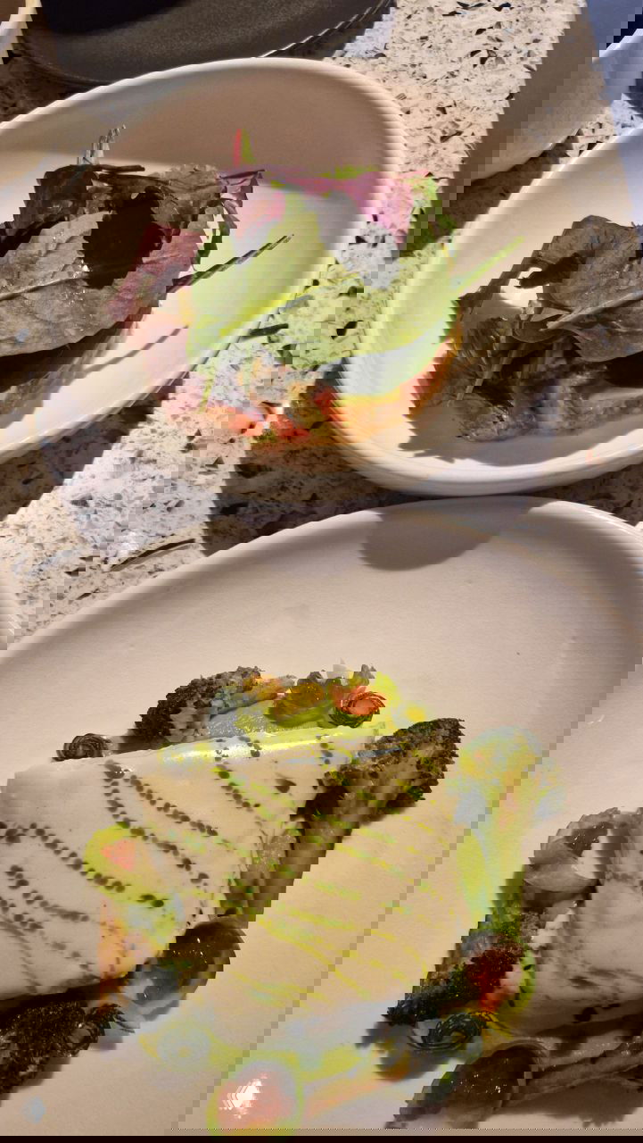 Два блюда на столе: сверху салат с зеленью, внизу стейк из трески с белым соусом и овощными акцентами — вид ужина перед театром.