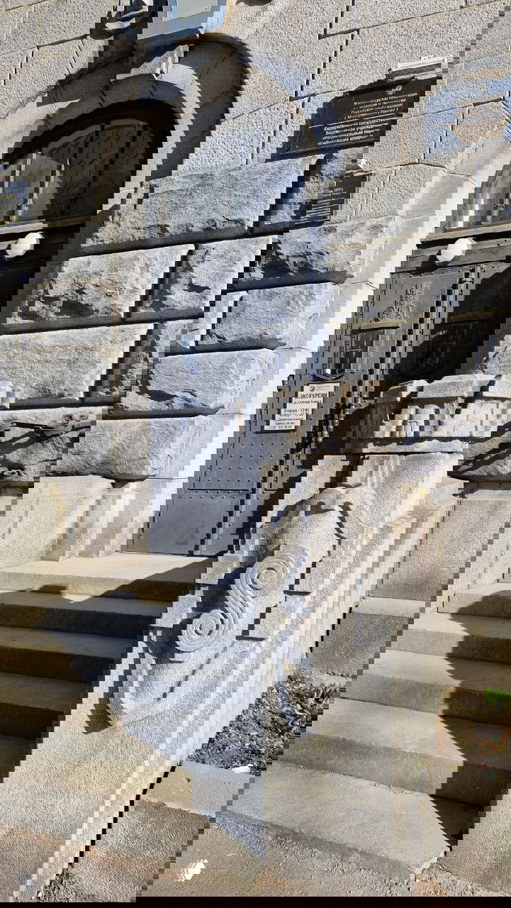 Главный вход с гранитными ступенями, декоративным пилоном и памятной табличкой — подробно отображён фасад Финляндского банка начала XX века.