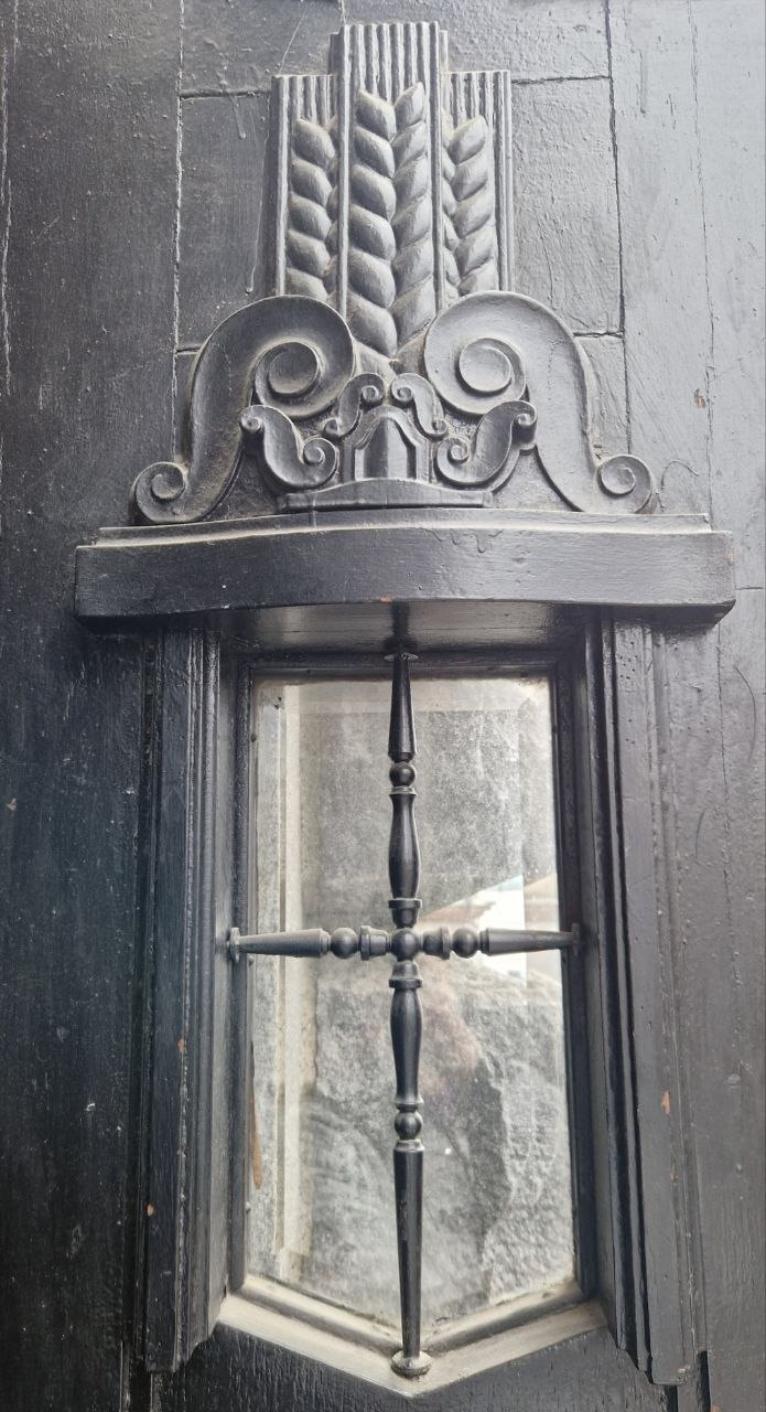 Декоративная деревянная отделка вокруг узкого окна и кованая решётка — пример художественной обработки элементов входной группы банка 1915 года.