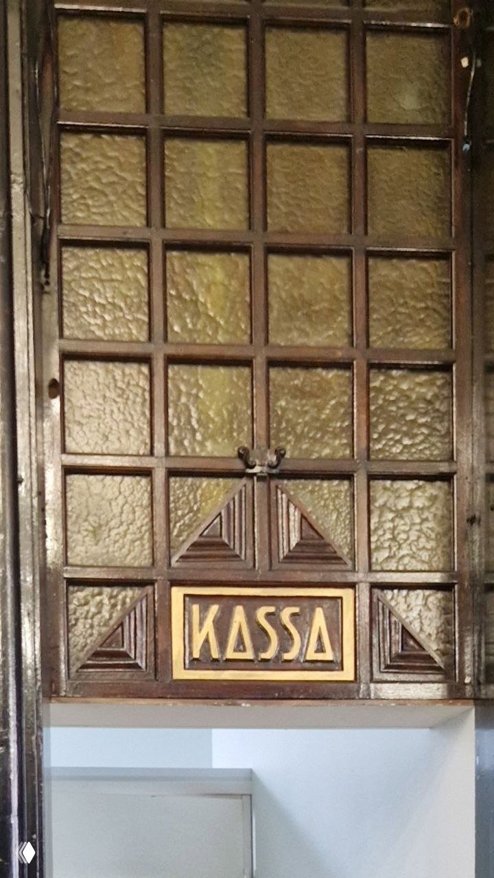 Деревянная перегородка с витражами и надписью «KASSA» — фрагмент кассовой зоны исторического оформления интерьера банка.