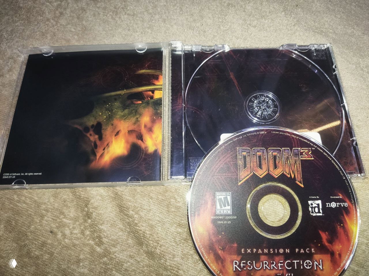 Открытая мелкая пластиковая коробка и диск Doom 3: Resurrection of Evil, видно внутреннее оформление и посадочное место для дисков.