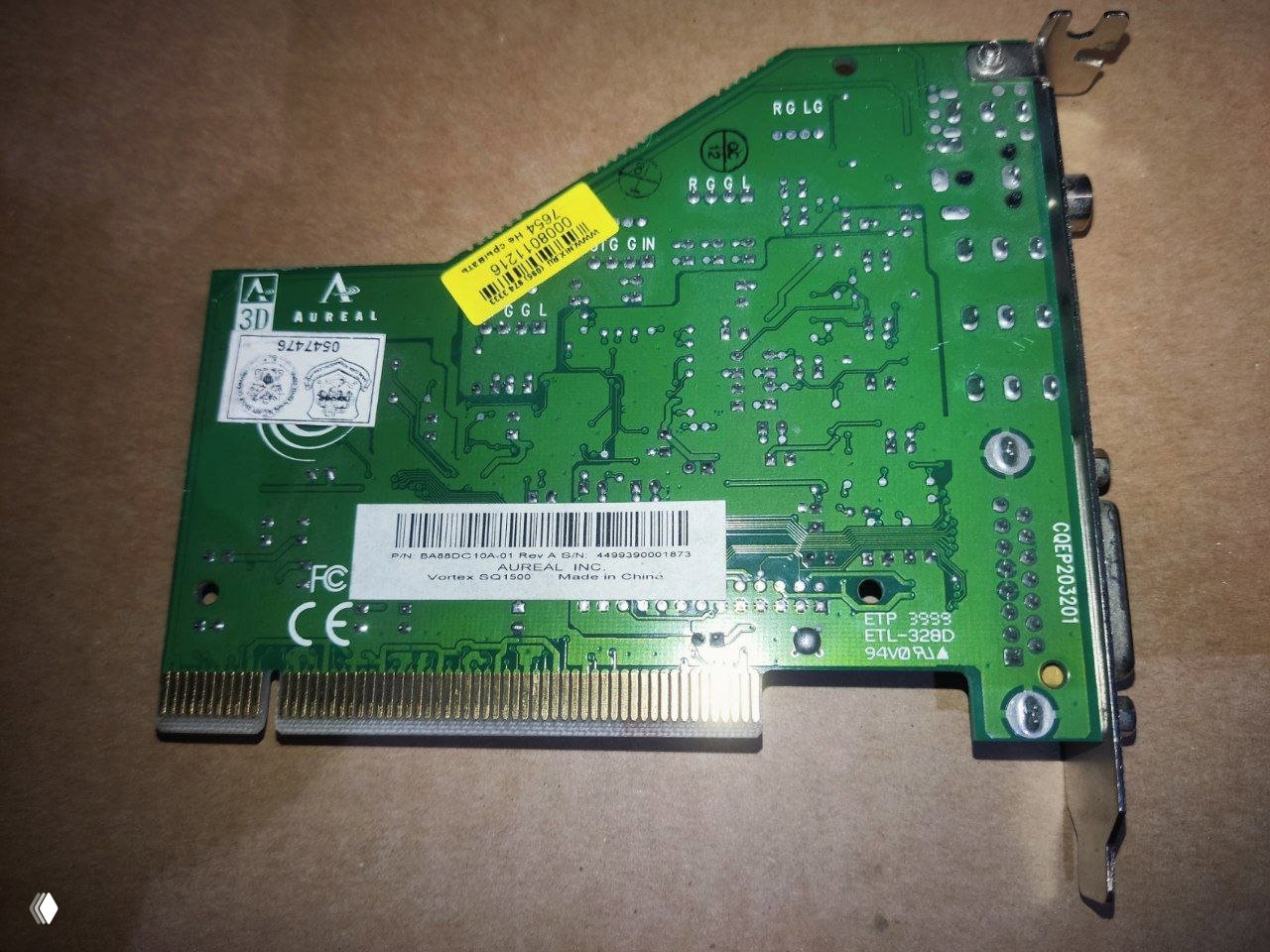 Обратная сторона аудиокарты Aureal Vortex AU8810 с заводскими наклейками, штрихкодом и контактной кромкой ISA на картонной подложке.