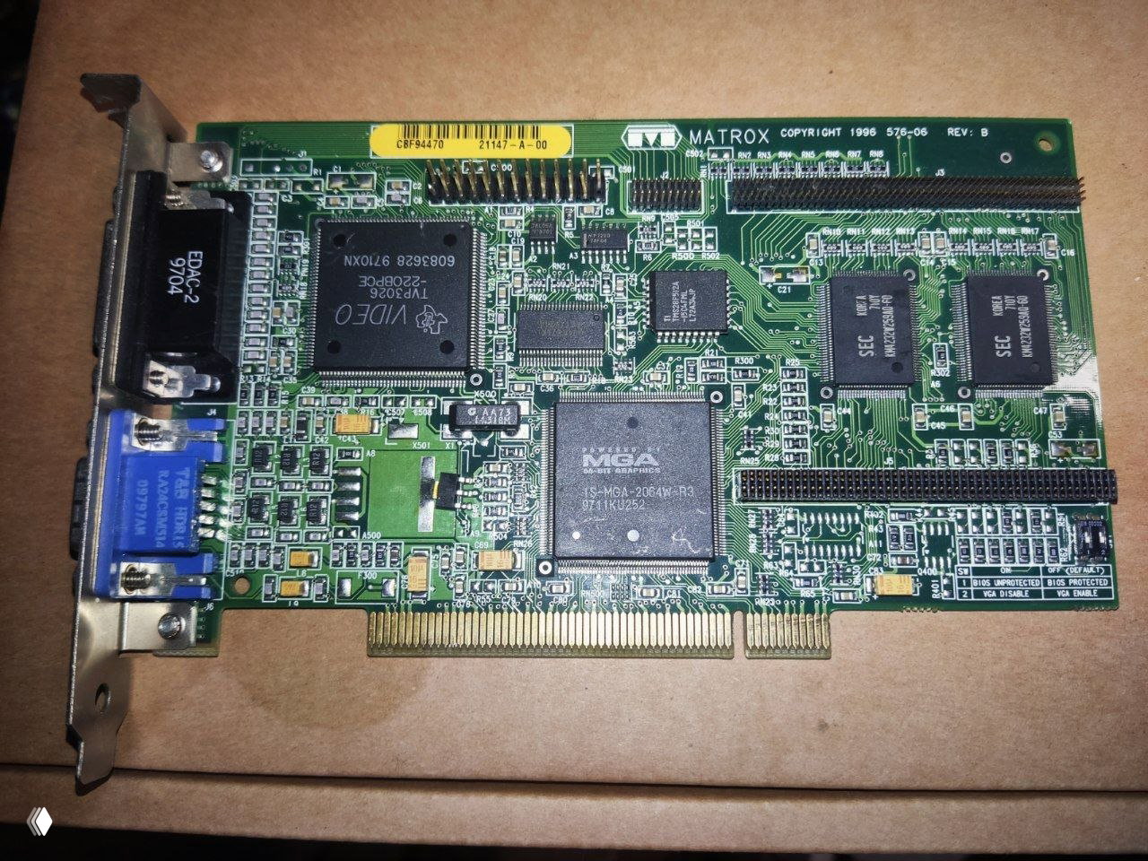 Видеокарта Matrox (MGA) на картоне: видна крупная микросхема MGA, память, разъёмы VGA и ISA-контакты — лицевая сторона платы.
