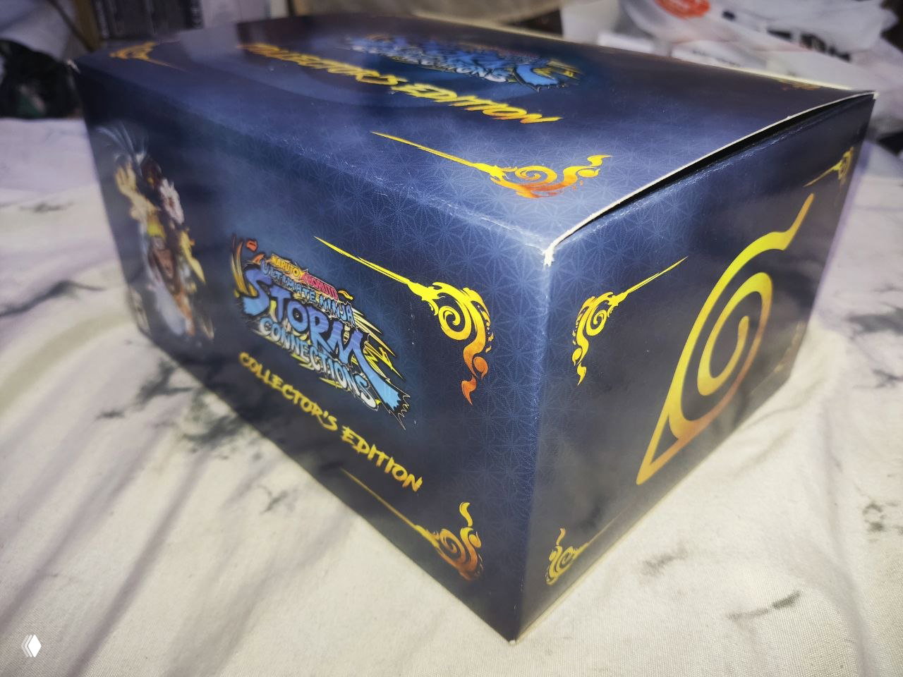 Угол коробки Naruto Collector's Edition крупным планом: видно надрыв и деформацию картонной кромки на стыке крышки, ракурс сбоку и сверху.