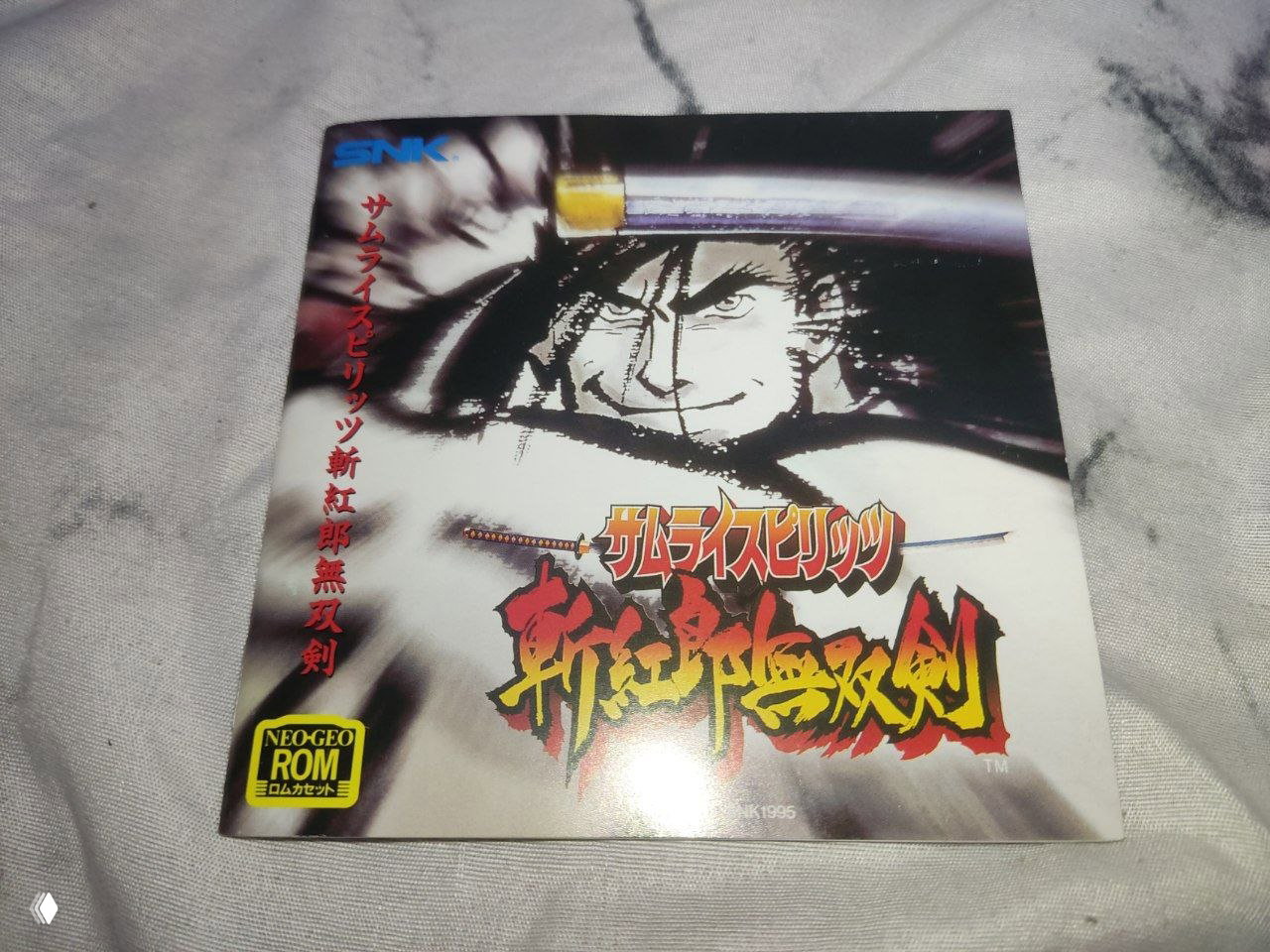 Лист компактного мануала игры 1995 года с изображением самурая и логотипами SNK и NEOGEO ROM на светлом фоне.