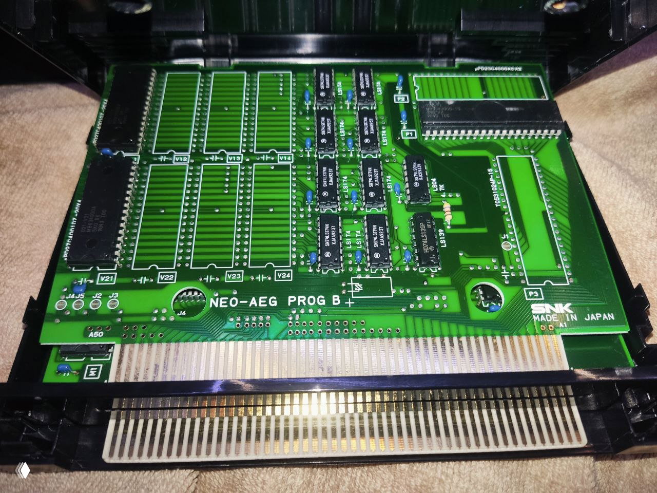 Вид печатной платы картриджа Neo Geo с контактной кромкой: открыта крышка, хорошо видны ламели, дорожки и установленные микросхемы для проверки подлинности.