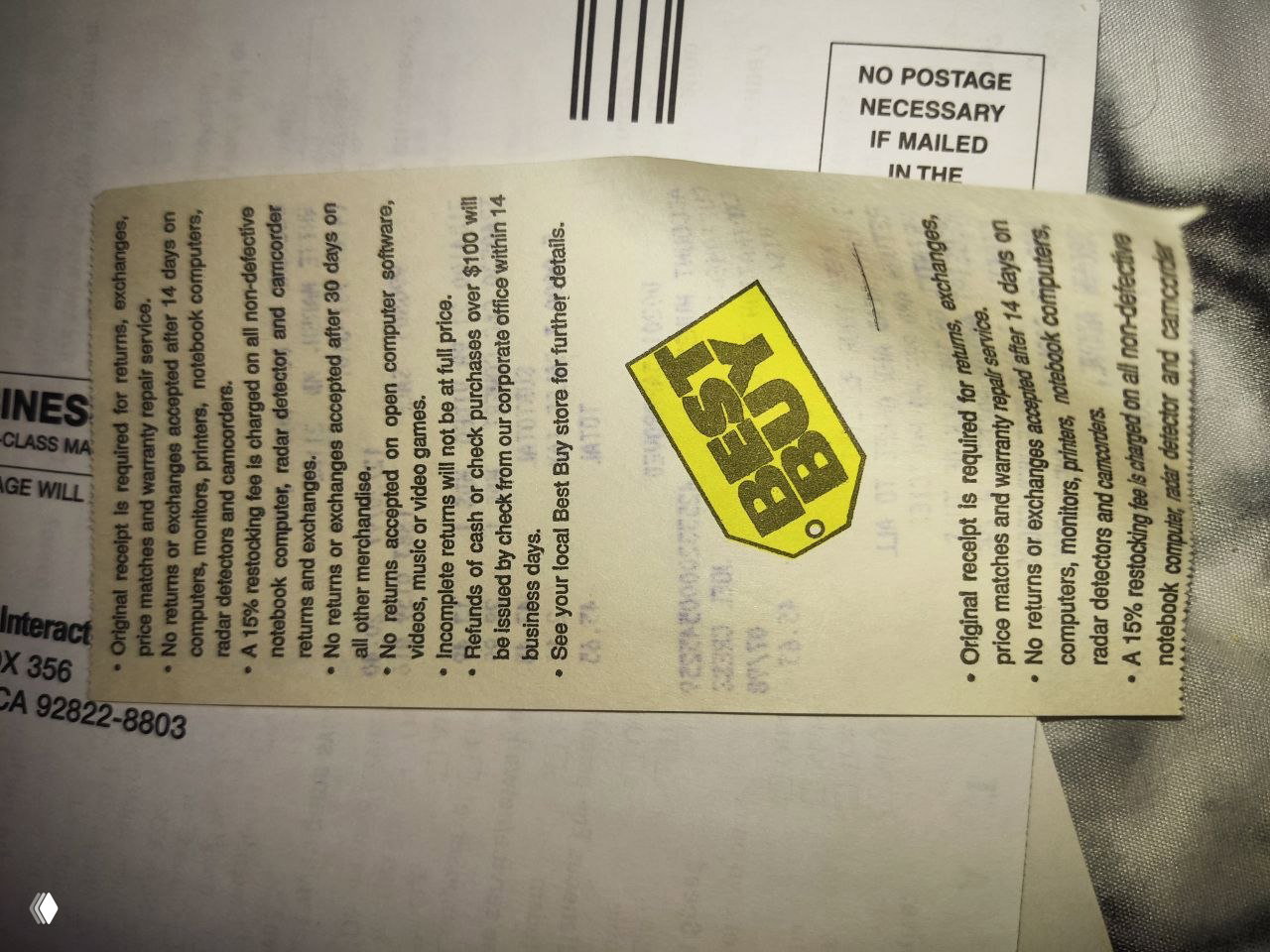 Обратная сторона чековой ленты с логотипом Best Buy и мелким печатным текстом условий возврата; на фоне виден почтовый конверт.