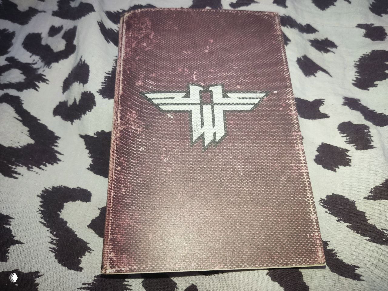 Фирменное плотное руководство Return to Castle Wolfenstein с потертостями, корешком и эмблемой на обложке, бумага похожа на плотный крафт или картон