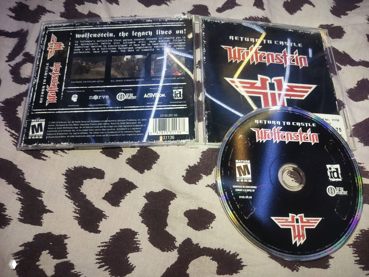 Джевел-кейс с диском Return to Castle Wolfenstein и внутренним оформлением обложки, диск положен рядом с коробкой, видны логотипы издателя и рейтинга ESRB