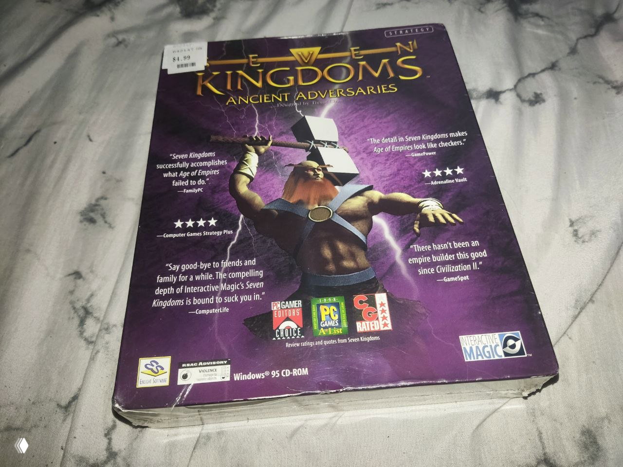 Обратная сторона коробки Seven Kingdoms с фиолетовым оформлением и цитатами; видны значки наград и ценник в левом верхнем углу коробки.