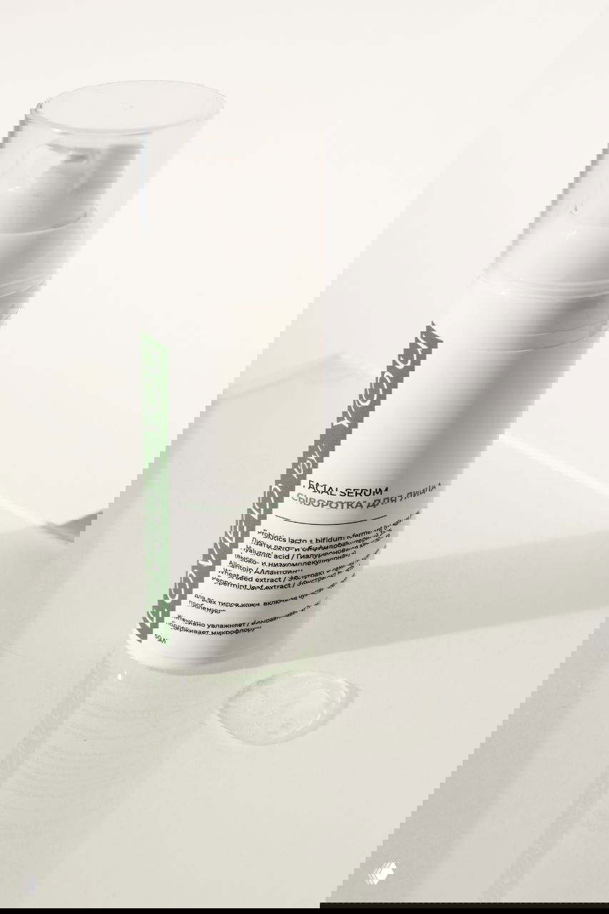 Флакон увлажняющей сыворотки Loved by You в белой упаковке на светлом фоне; рядом видна капля прозрачной сывороточной текстуры, акцент на бренде.