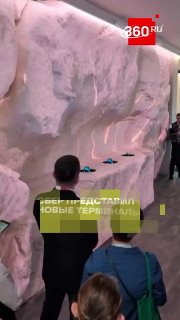 Демонстрация терминала «Нео» на стенде Сбера (ПМЭФ‑2026): люди смотрят устройство с левитирующим дисплеем и лидаром.