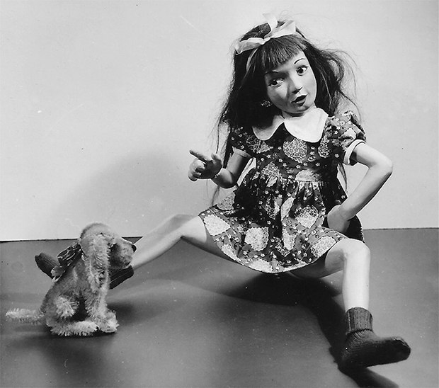 Чёрно‑белая фотография девочки‑куклы в игривой позе рядом с игрушкой — сочетание наивности и тревожности образа.