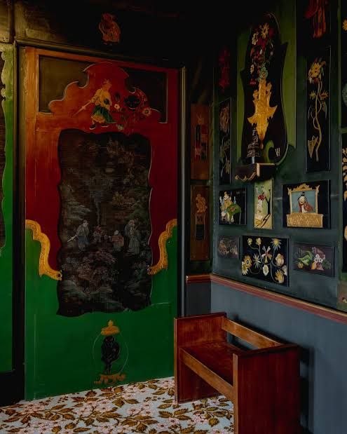 Зелёная дверь и скамья внутри дома Виктора Гюго, вокруг мелкие настенные витрины и элементы шинуазри — камерный фрагмент музейного интерьера.