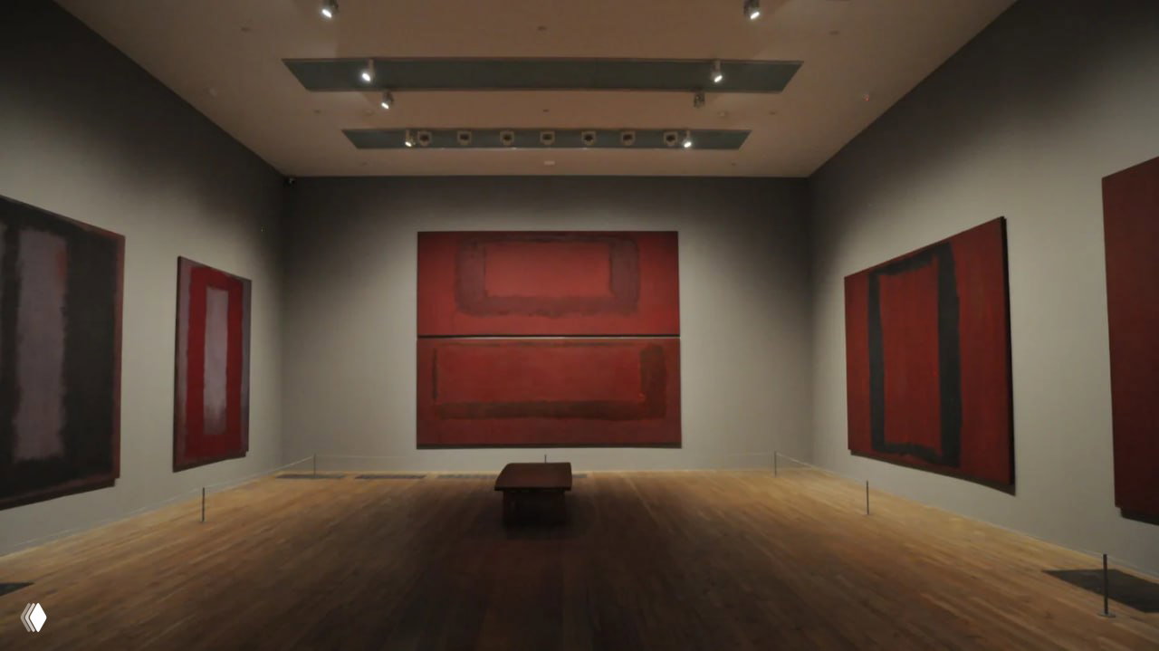 Галерея с работами Марка Ротко: большие полотна красно-бурой гаммы на нейтральных стенах, ровное музейное освещение и пустой центр зала, подчёркивающий серьёзный характер экспозиции.
