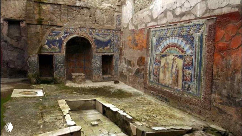 Интерьер восстановленного участка виллы папирусов в Геркулануме: фрагменты фресок на стенах и археологические руины на месте античных свитков.