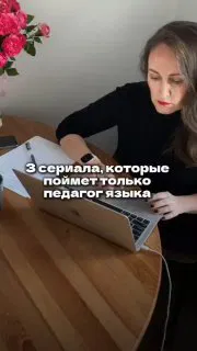 Женщина за ноутбуком за круглым столом с цветами рядом; на изображении текст «3 сериала, которые поймет только педагог языка», атмосфера рабочего вечера и размышлений.