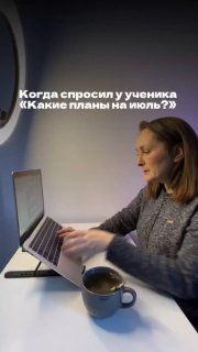Женщина‑преподаватель за ноутбуком с кружкой на столе, записывает видео у окна; на снимке видна надпись «Какие планы на июль?»