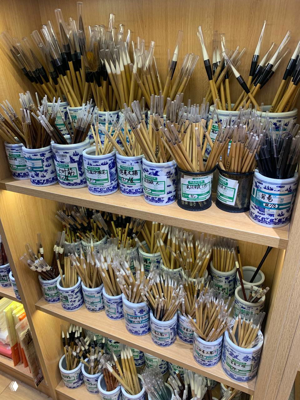 Полки с множеством кистей для каллиграфии и рисования в традиционных фарфоровых подставках в магазине сувениров.