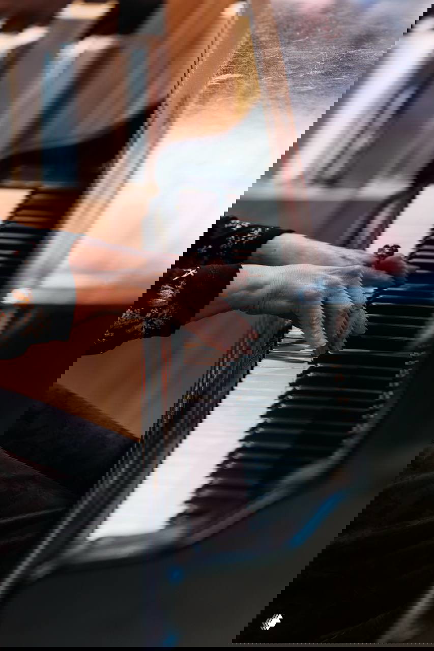 Руки на клавишах рояля в экспозиции музея: крупный план игры на инструменте, создающий атмосферу мероприятия и исторического пространства