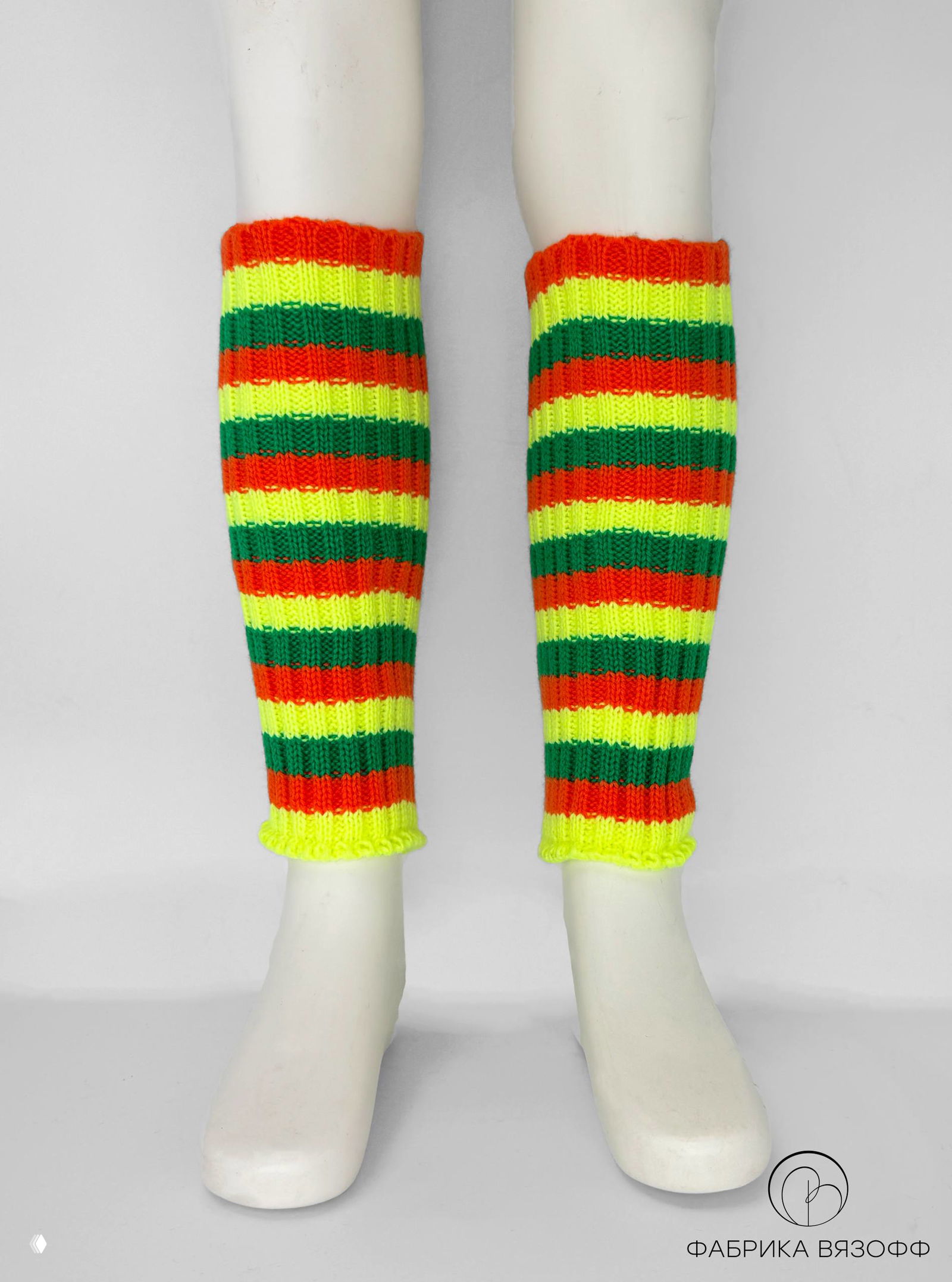 Фотография пары неоновых полосатых гетр в стоячем ракурсе на манекенных ногах; яркие цвета и равномерный ритм полос на нейтральном фоне.