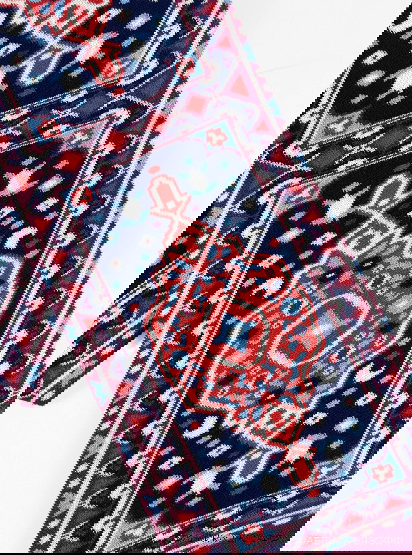 Фрагмент шарфа с ковровым мотивом в тёмно‑синих и красных оттенках, видна тонкая детализация рисунка и хороший контраст цветов на ткани.