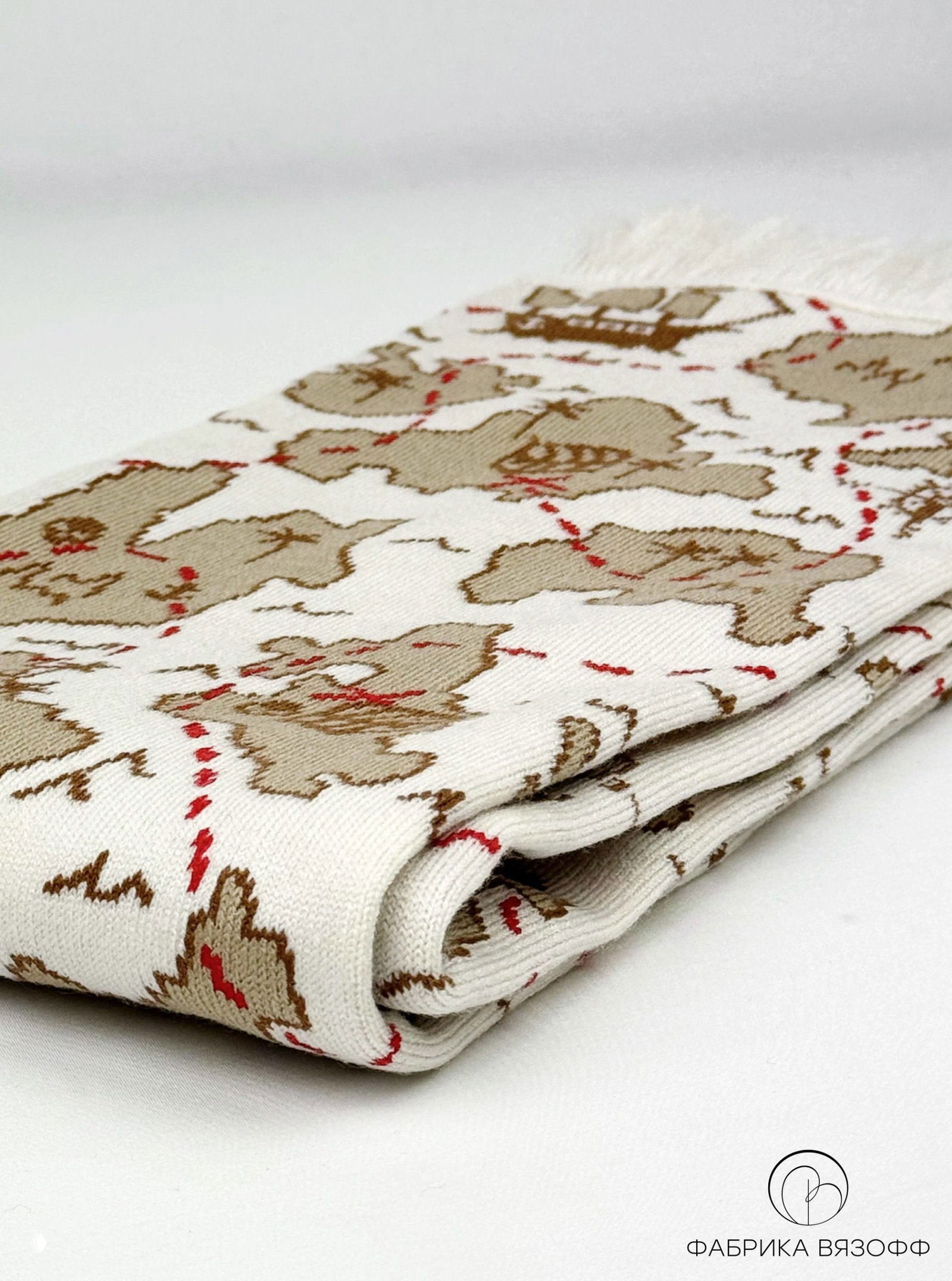 Сложенный шарф с картографическим рисунком: аккуратно сложенная вязка, видна фактура и плавность бежевых оттенков на белом фоне.