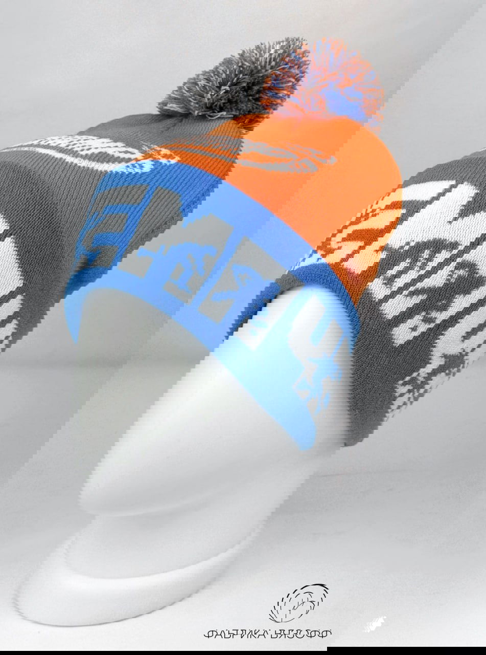 Профильный вид шапки на манекене: синий отворот с белыми буквами, оранжевый верх и помпон демонстрируют сочетание цветов командного мерча.