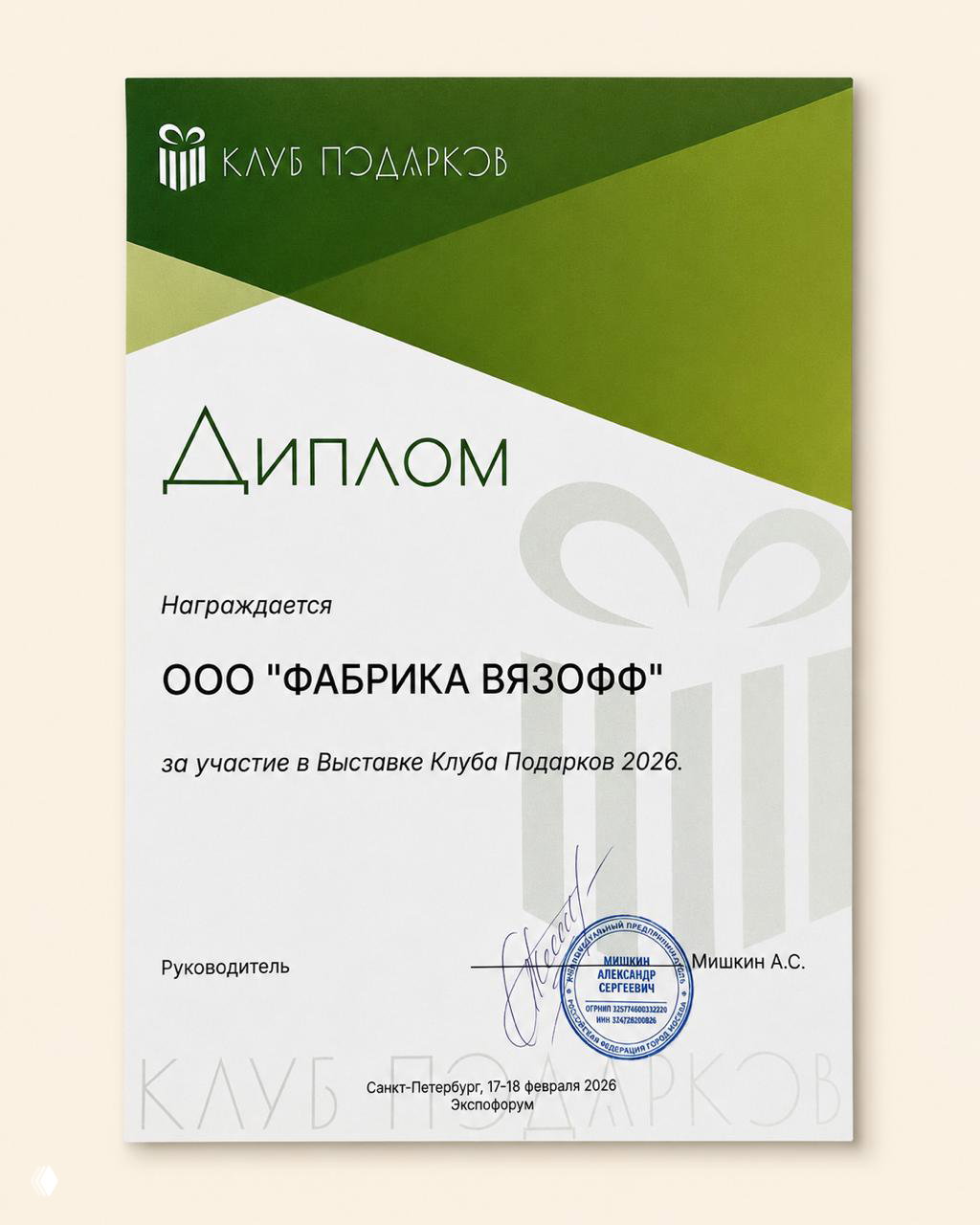 Белый диплом с зелёными элементами «Клуб подарков», в котором награждается ООО "ФАБРИКА ВЯЗОФФ" за участие в выставке клуба подарков, видна подпись и печать организатора.