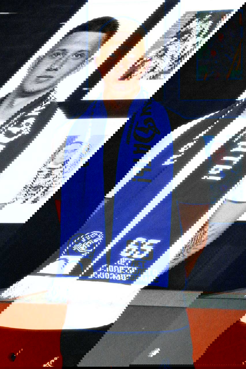 Модель в белой футболке носит синий шарф ФК «Динамо» с эмблемой и подписью «65 лет с полёта в космос», видна текстура вязаного полотна.