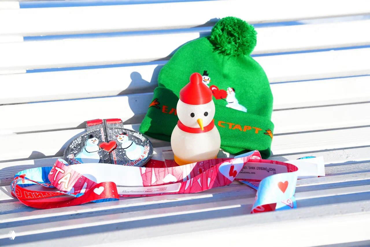 Зелёная вязаная шапка с помпоном, рядом медаль и ленточка на деревянной скамье — композиция послевкусия мероприятия и подарка участникам.