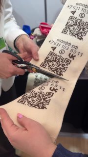 Крупный план: руки ножницами разрезают вязаную полоску‑визитку с QR‑кодами и номером, видно текст «вязофф.рф» на полотне.
