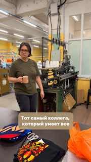 Сотрудник фабрики у кругловязальной машины в мастерской ВЯЗОФФ: стоит с кружкой, видна производственная обстановка и оборудование.