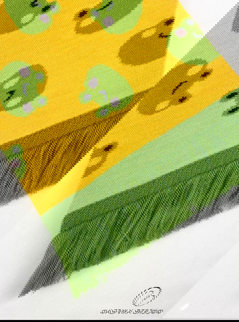 Крупный план жёлтого шарфа с лягушатами, видна текстура акрилового полотна и ряды жаккарда, съёмка на белом фоне.