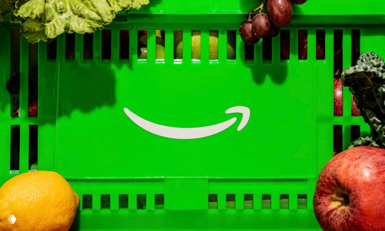 Зелёный ящик Amazon с белой «улыбкой» среди фруктов и овощей, подчёркивающий визуальную идентичность Amazon Fresh и использование насыщенного зелёного цвета.